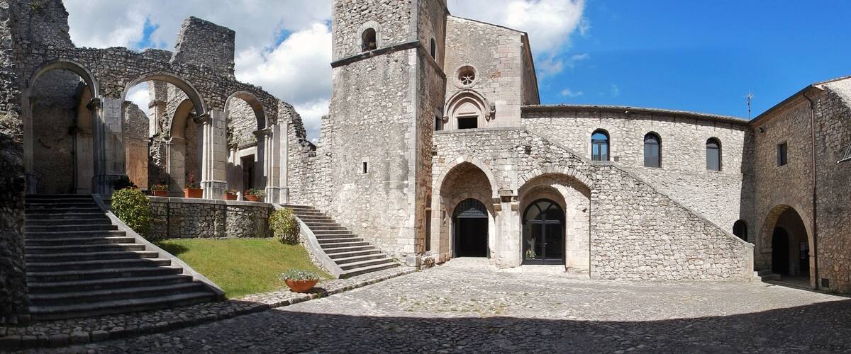 An ancient stone building with arched doorways and a central tower.