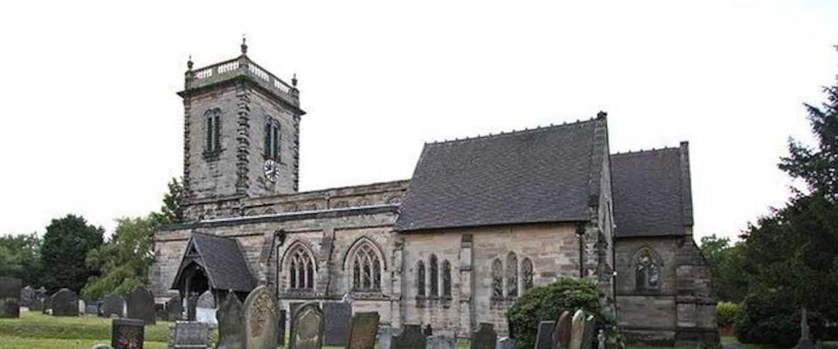 A church with a tower and multiple tombs in the foreground.