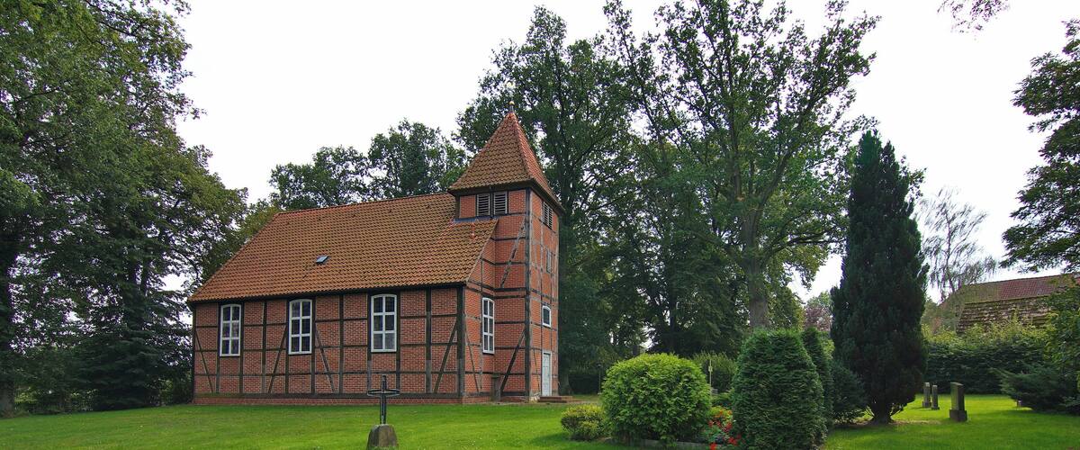 A traditional half-timbered house with a steeply pitched roof, surrounded by a well-maintained lawn and mature trees.