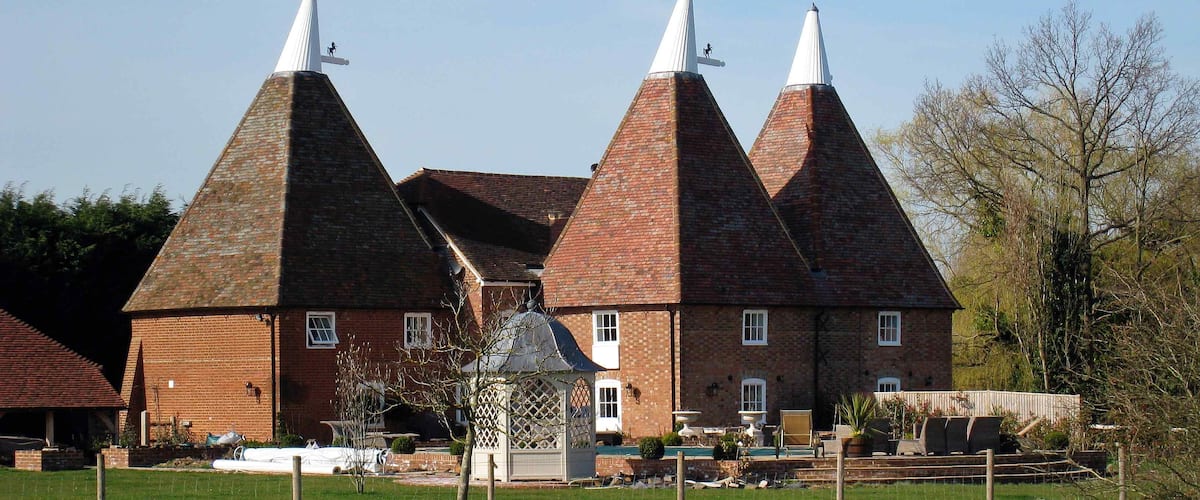 A large brick building with multiple conical roofs and a small gazebo in the foreground.