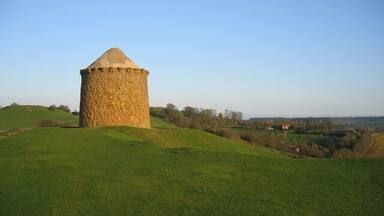 A stone tower on a grassy hill with a clear sky.