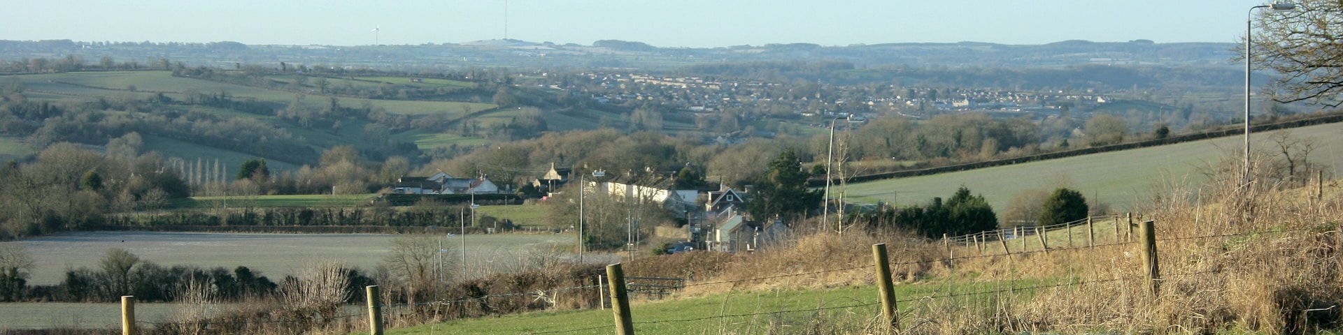 South west from Tunley Hill A fence blocks our path, Meadgate is at the bottom of the hill and Paulton is further over. The high point on the horizon to the left is Pen Hill with its TV transmitter ST5648
