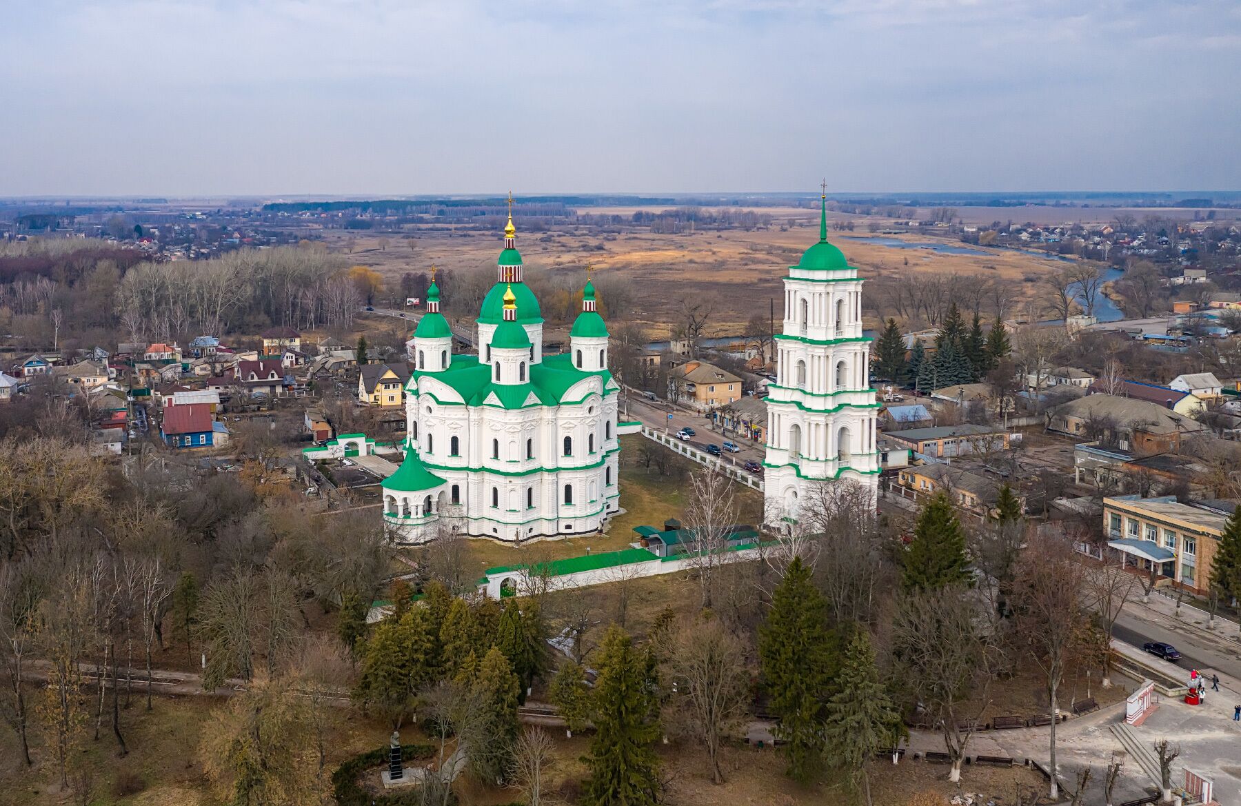 A large white church with green domes and a bell tower.