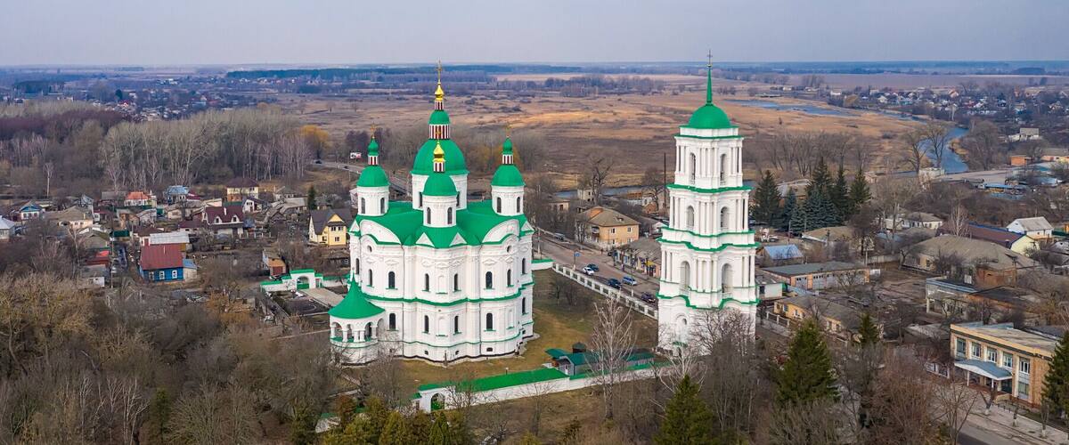 A large white church with green domes and a bell tower.