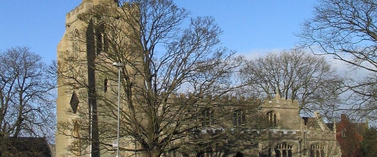 A church with a tall spire and a stone building with arched windows.