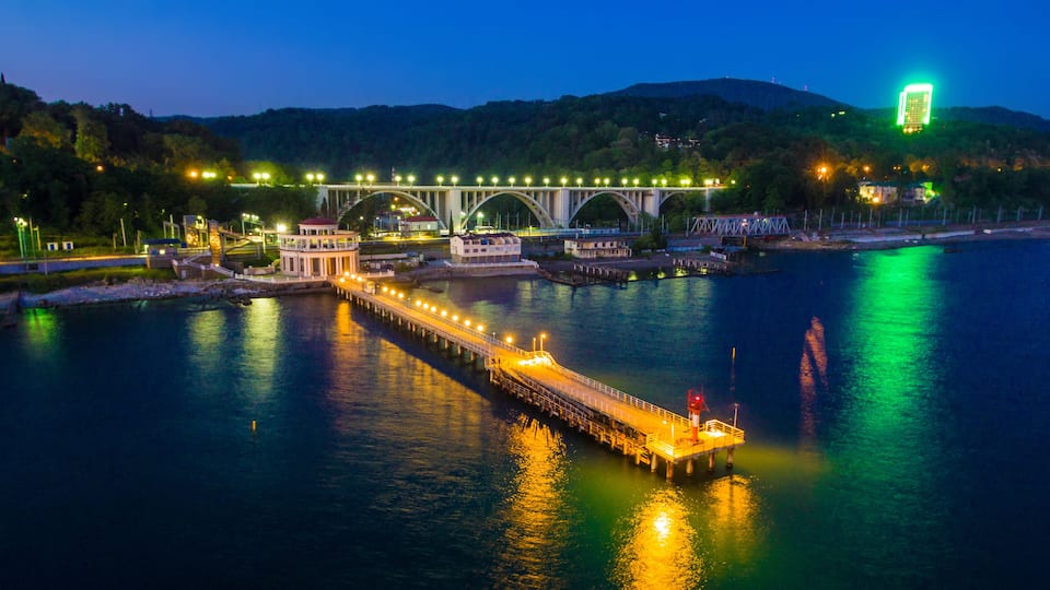 A bridge with lights, a dock, and a hill in the background.
