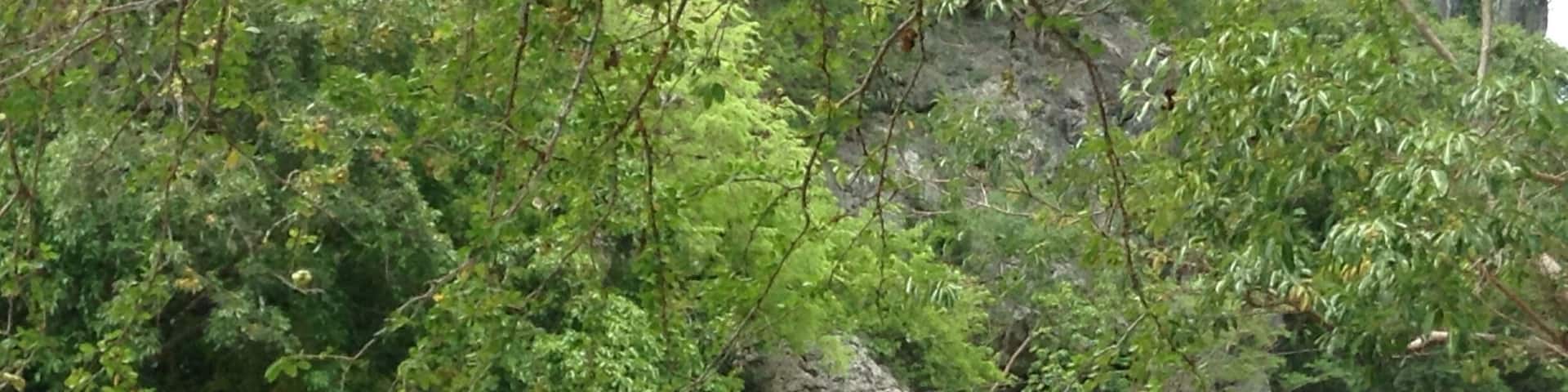 A person walking on a rope between rocks by a body of water.