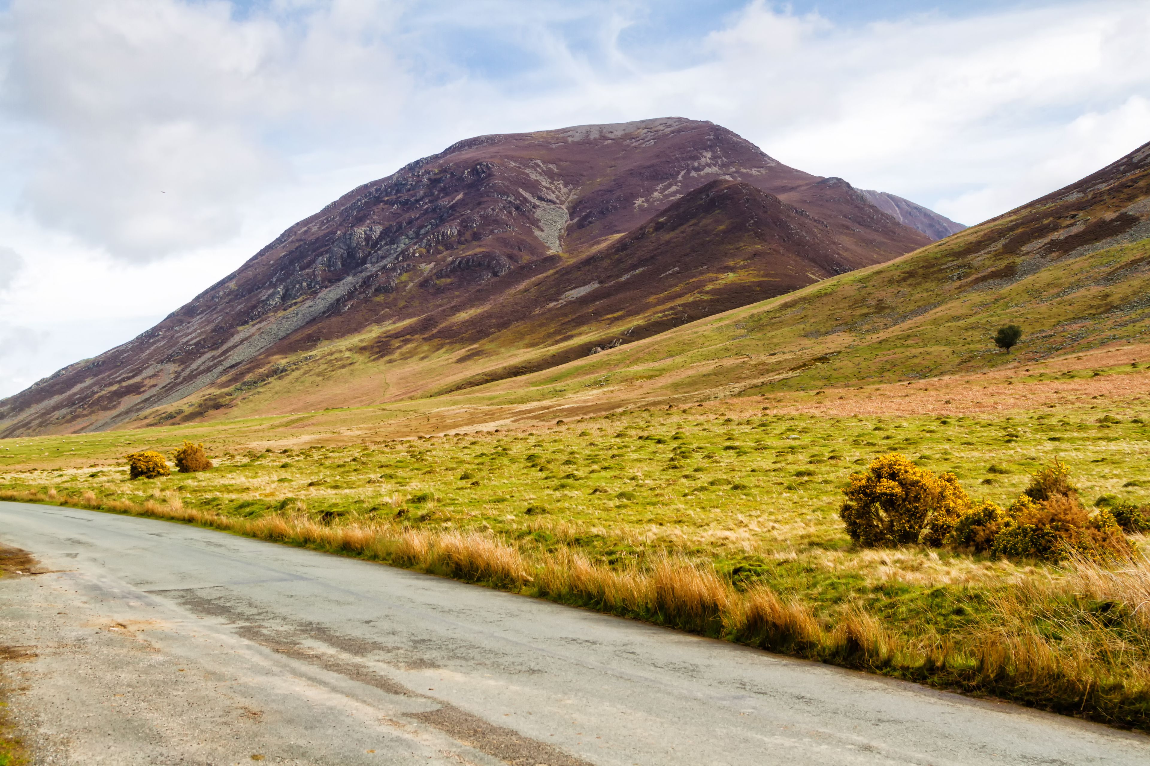 A winding road through a hilly landscape with a prominent mountain in the background.