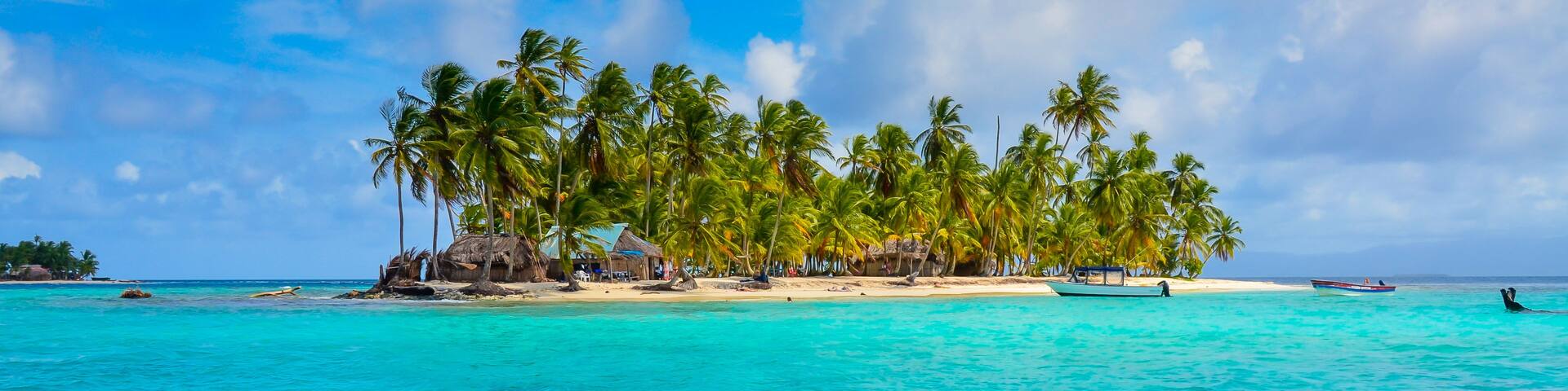 A tropical island with clear turquoise waters, palm trees, and thatched-roof huts.