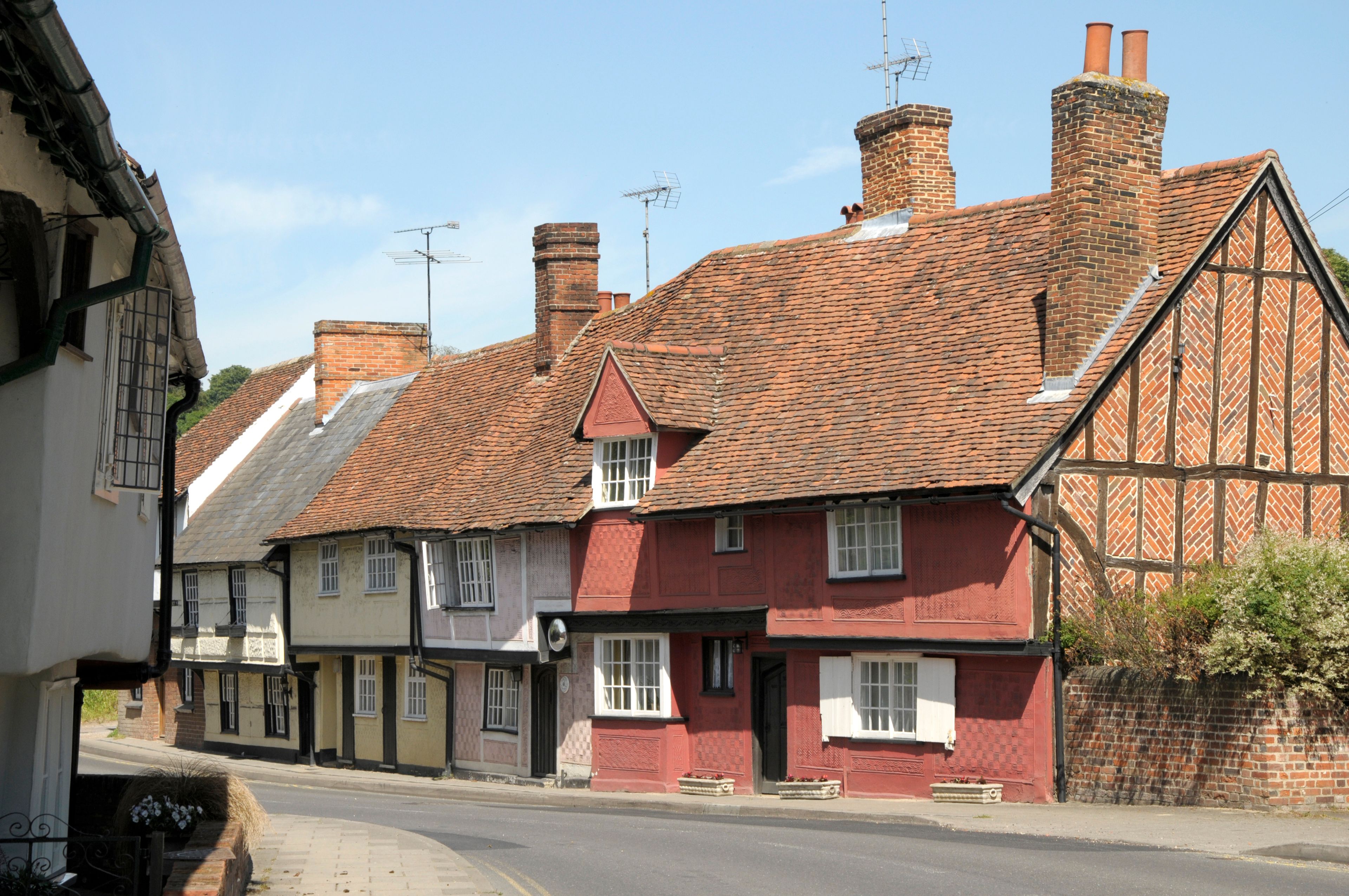 A street lined with traditional half-timbered houses with red brick chimneys and white window frames.