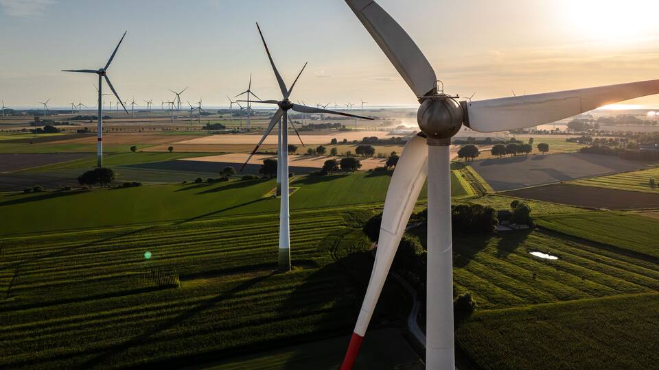 A landscape with multiple wind turbines and fields.