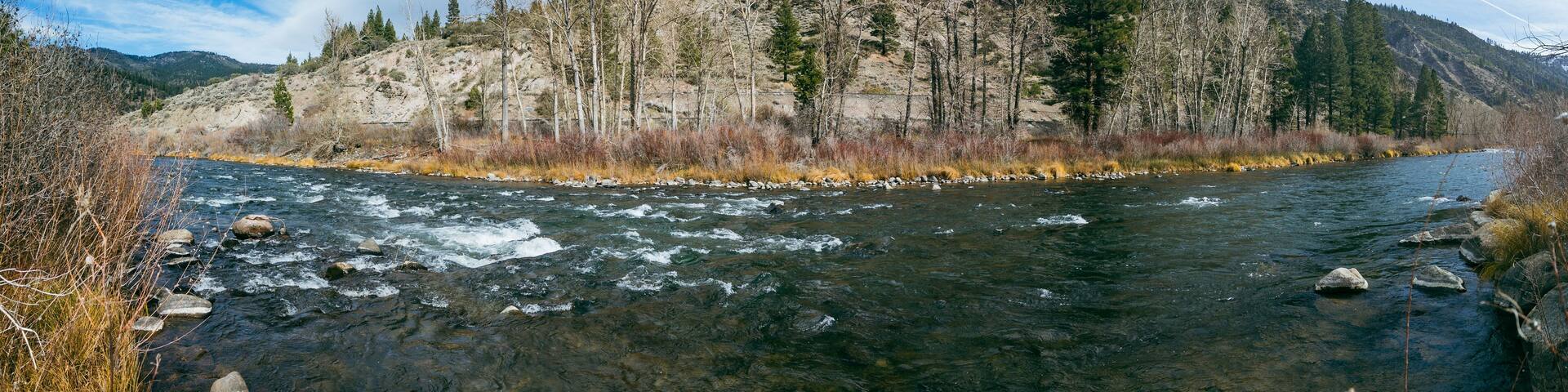 A river flowing through a mountainous landscape with rocky terrain and sparse vegetation.