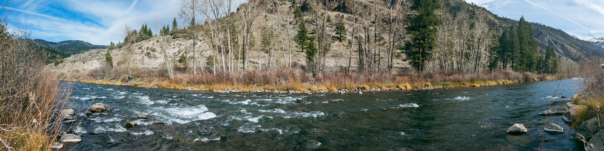 Rio serpenteando por uma paisagem montanhosa com terreno rochoso e vegetação escassa.