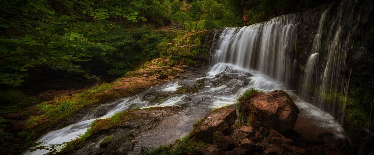 A waterfall cascading over rocks in a forested area.