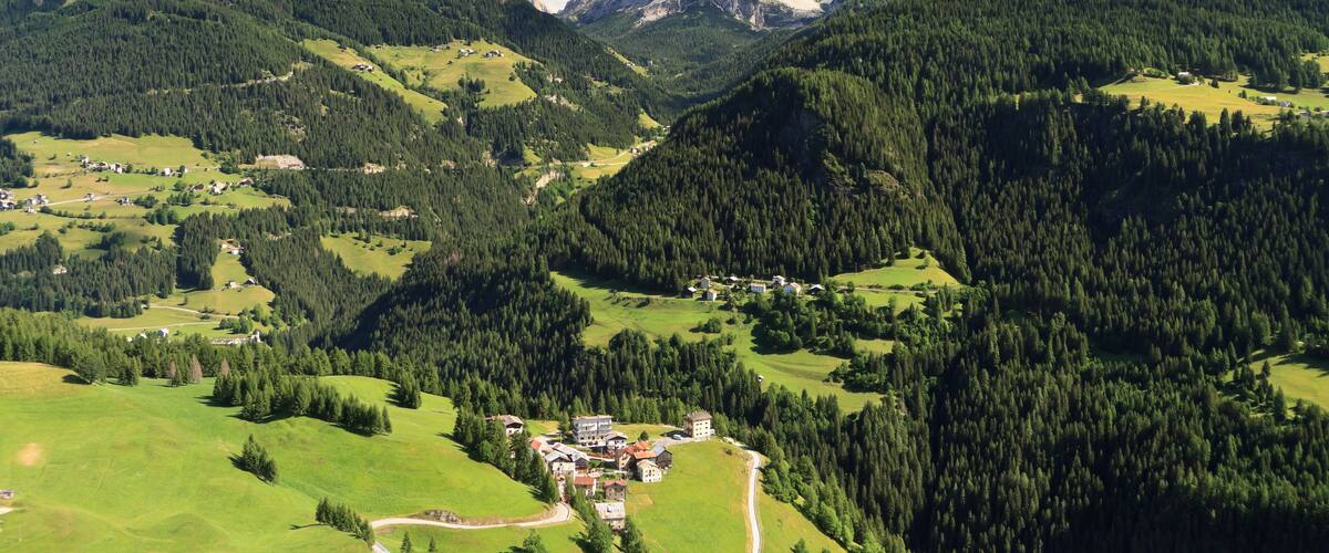 A mountainous landscape with a village nestled among green valleys and dense forests.
