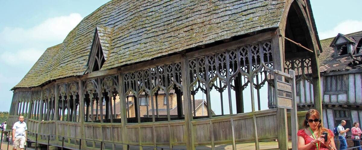 A historic wooden structure with a steeply pitched roof and intricate window designs.