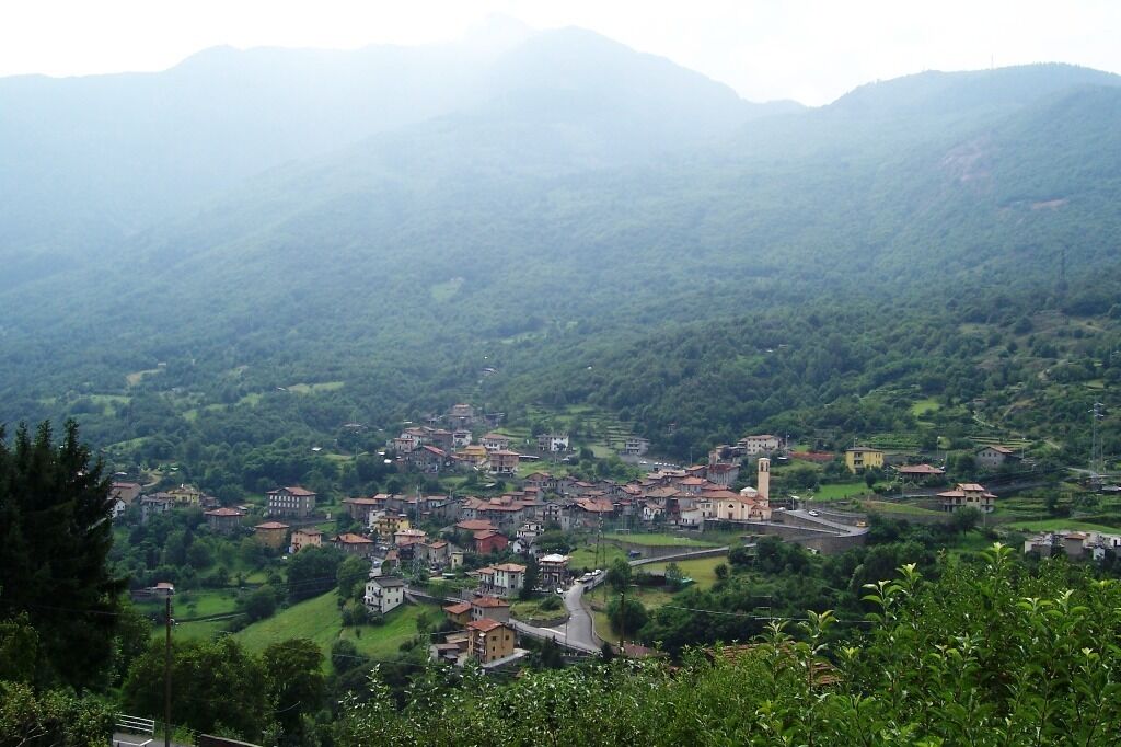 A mountainous village with terraced fields, a prominent church, and scattered houses.