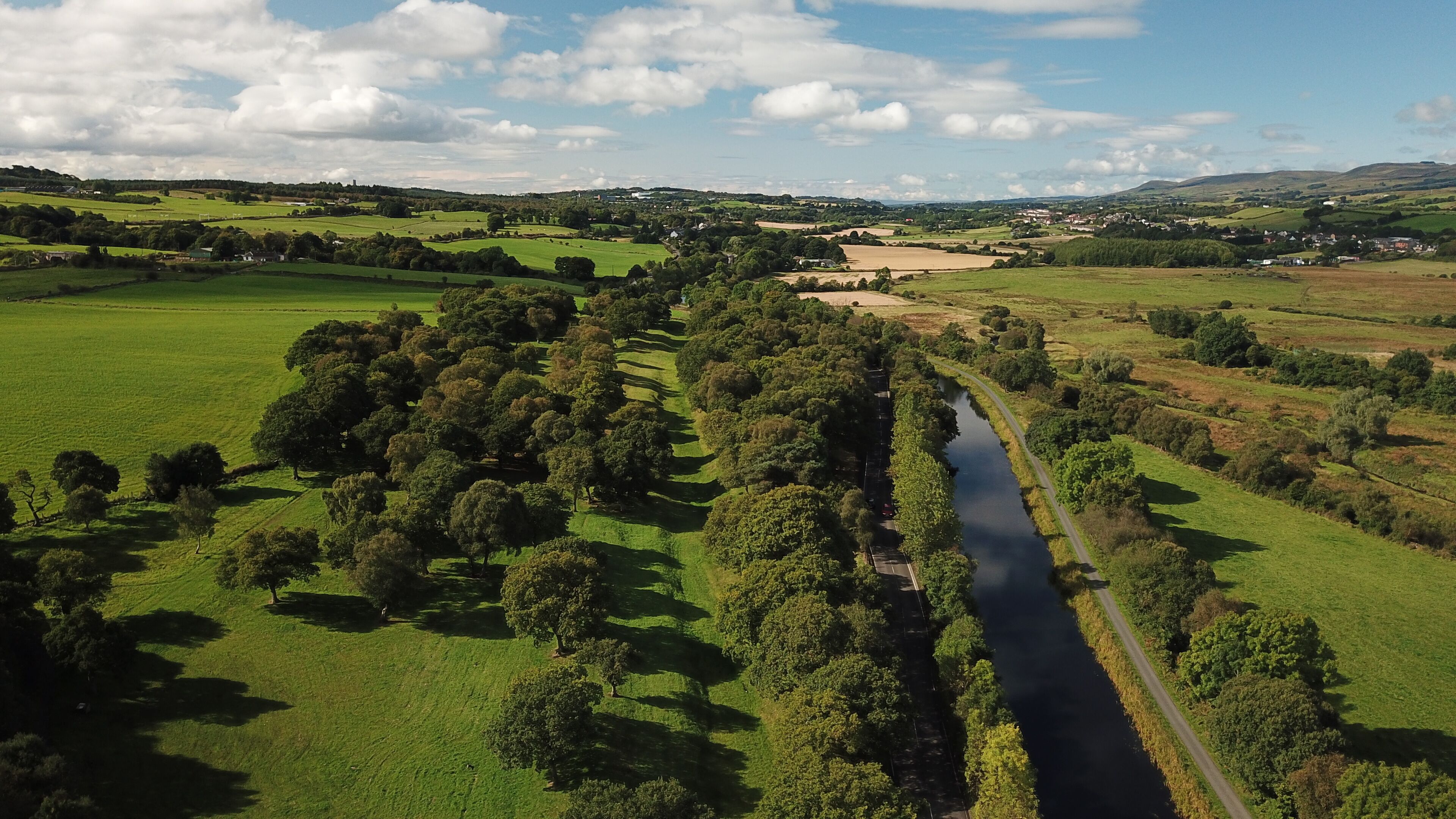 A river winding through a lush green valley with scattered trees and distant hills.