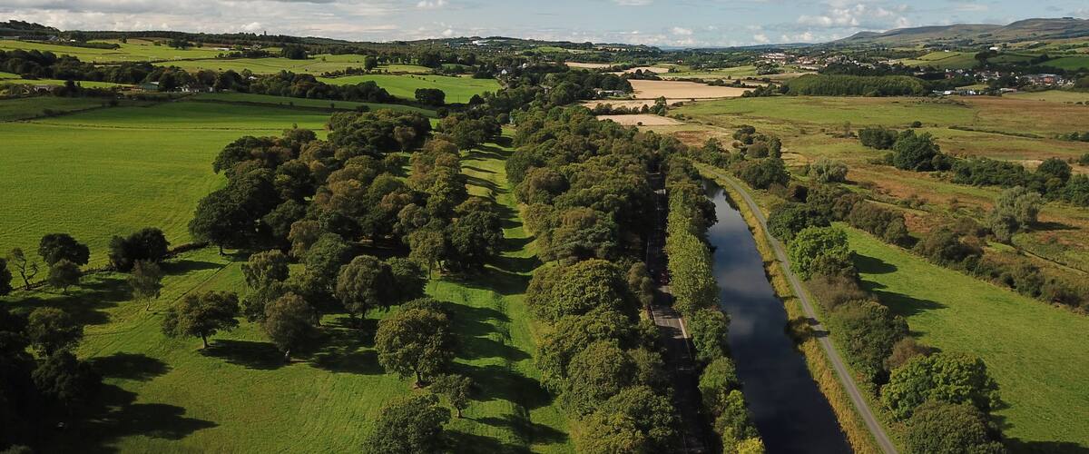 A river winding through a lush green valley with scattered trees and distant hills.