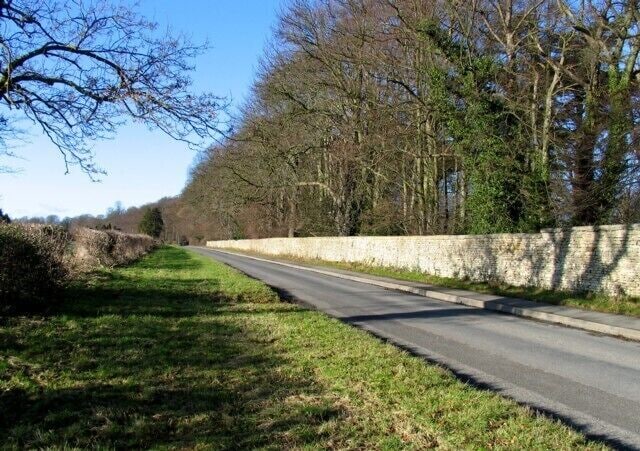 Oakham Road westwards The boundary wall of Exton Hall park is to the right.
