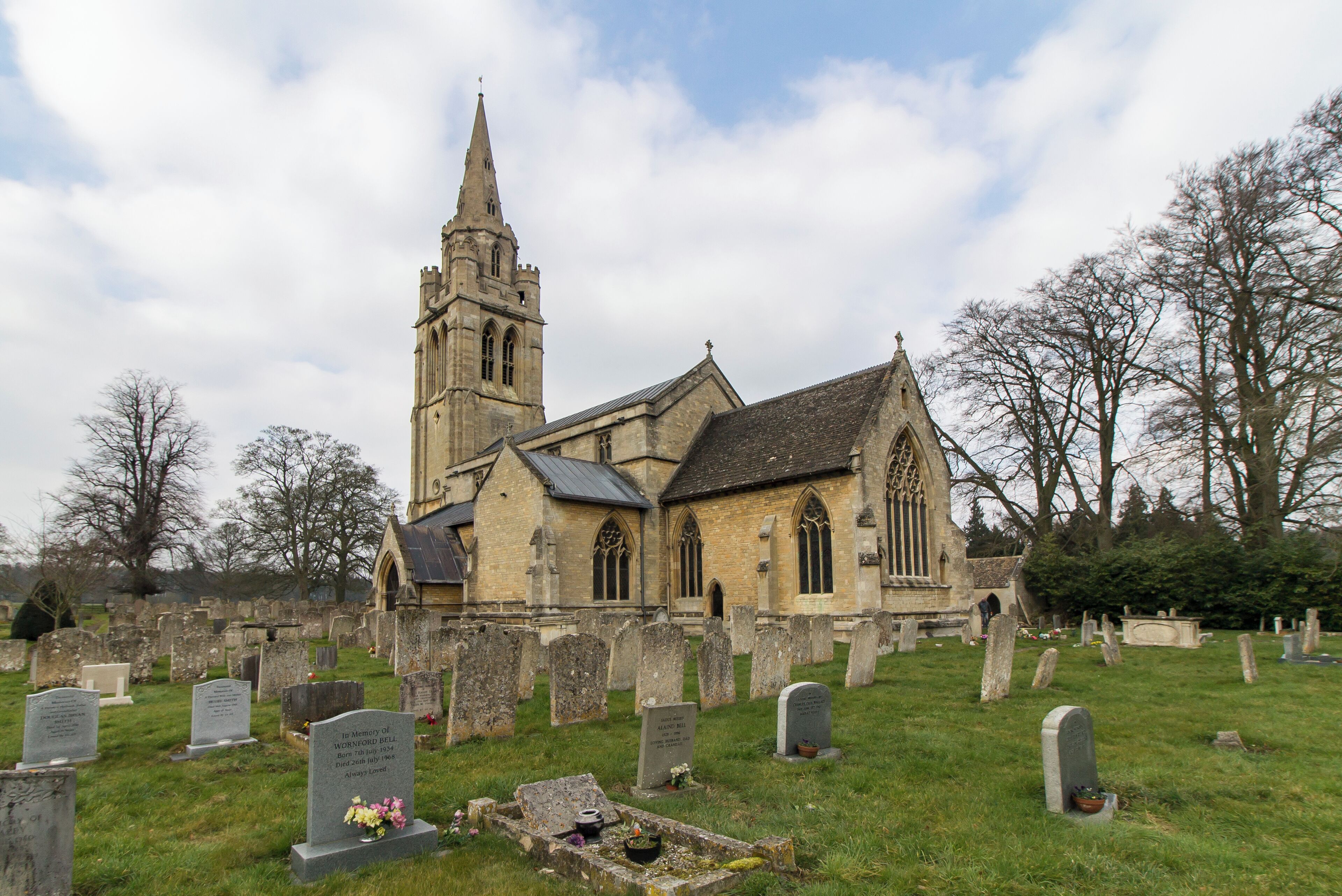 A historic church with a tall spire and a graveyard in front.