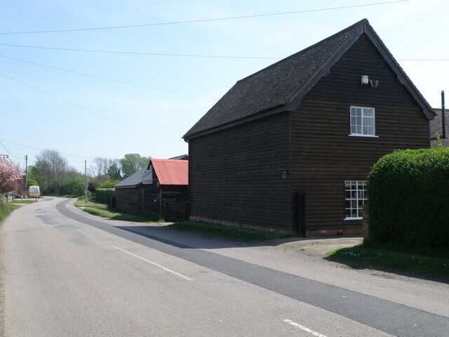 A rural road with a wooden building and a red-roofed structure.