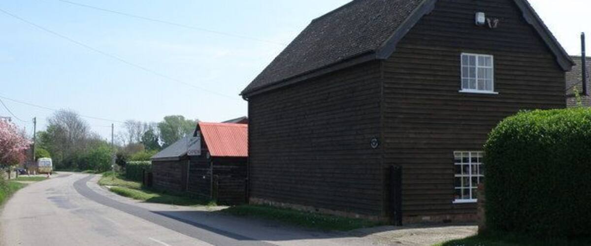 A rural road with a wooden building and a red-roofed structure.