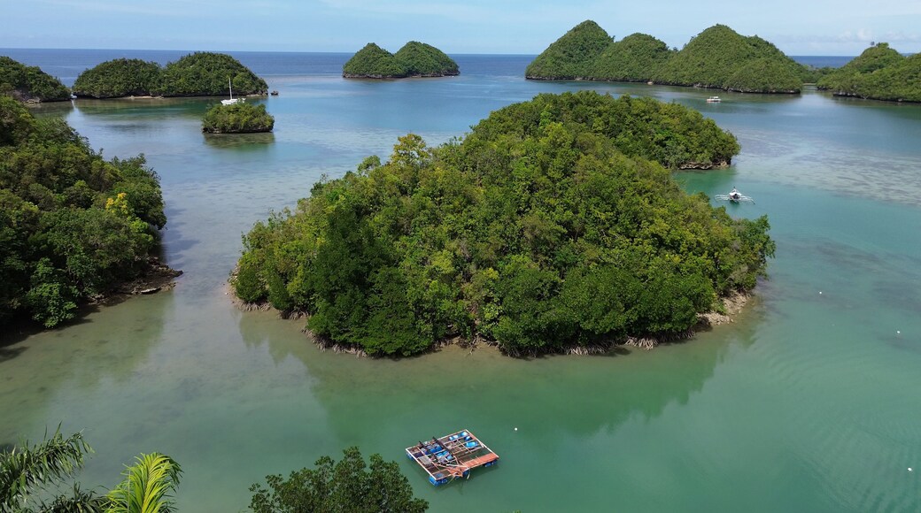 A tropical island surrounded by clear waters with a small boat anchored nearby.