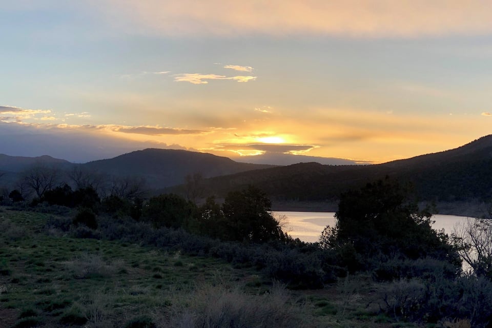 A sunset over a lake surrounded by hills.