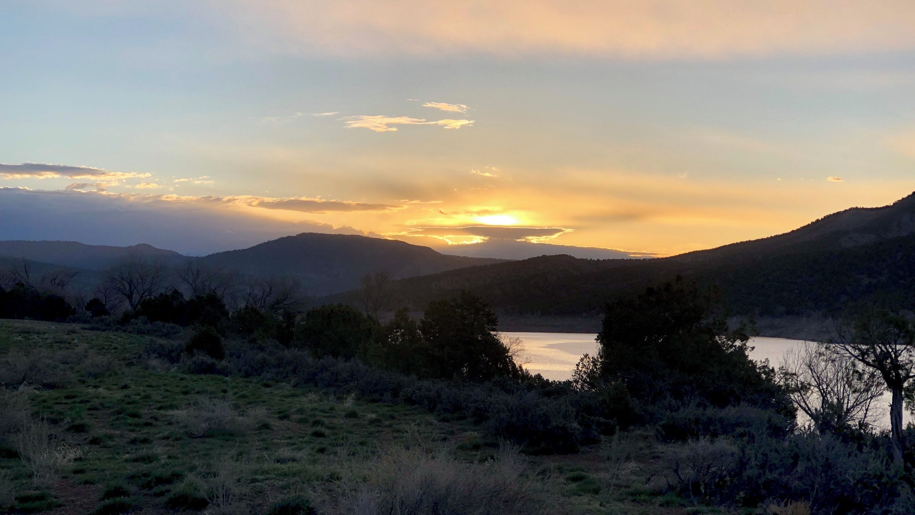 A sunset over a lake surrounded by hills.