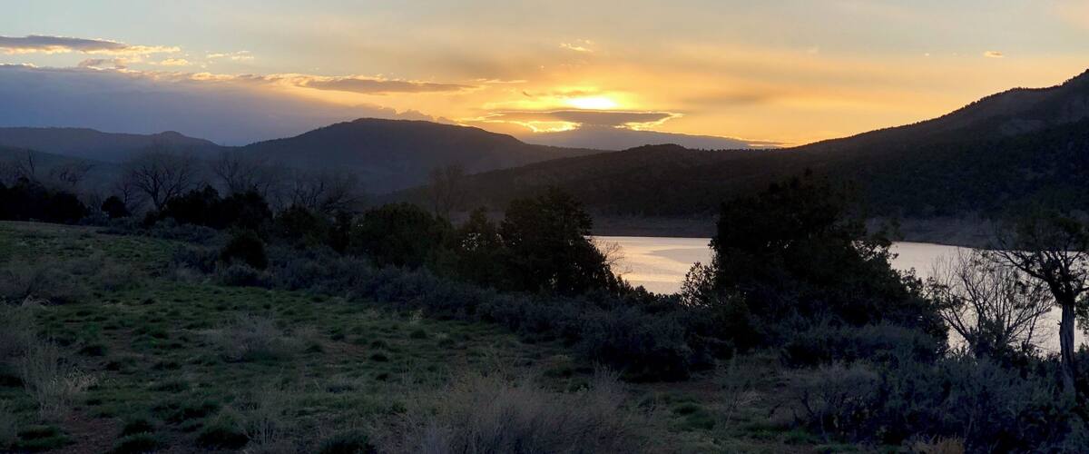 A sunset over a lake surrounded by hills.