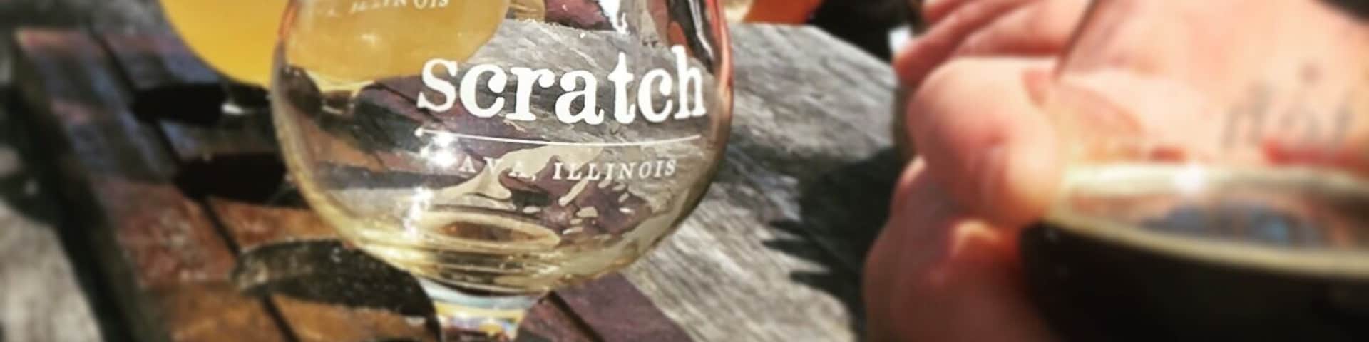 A wooden table with several glasses of beer, one prominently labeled 'scratch' with 'Illinois' visible.