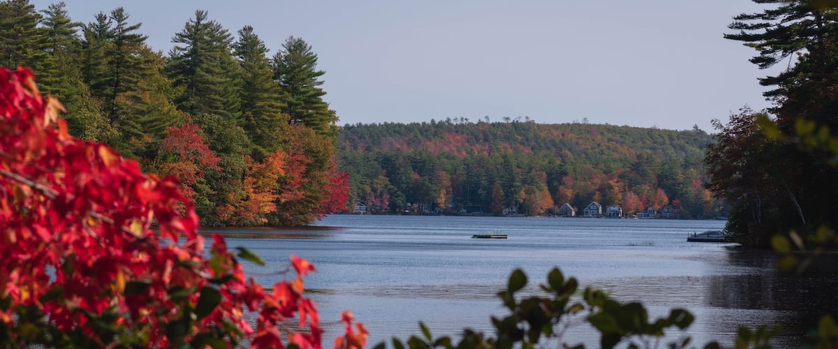 A calm lake surrounded by autumn-colored trees and a small boat.