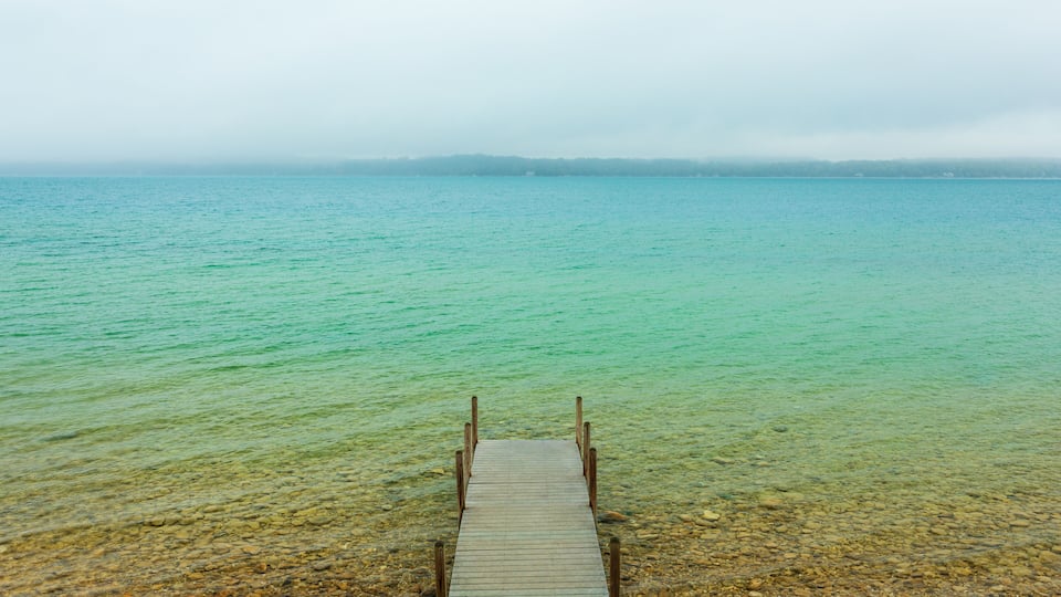 A wooden pier extending into a calm, turquoise lake surrounded by rocky terrain.