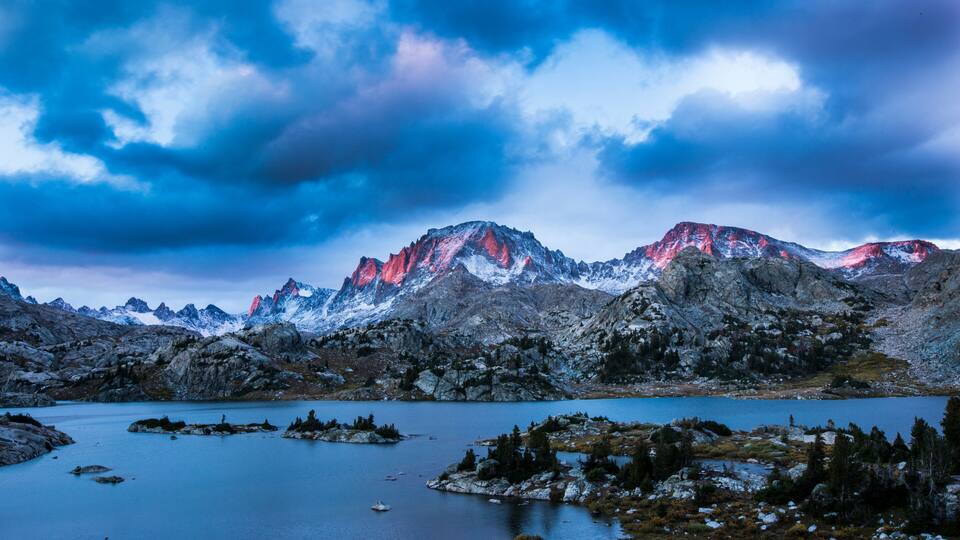 A mountainous landscape with a lake and snow-capped peaks.