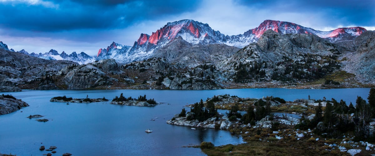 A mountainous landscape with a lake and snow-capped peaks.