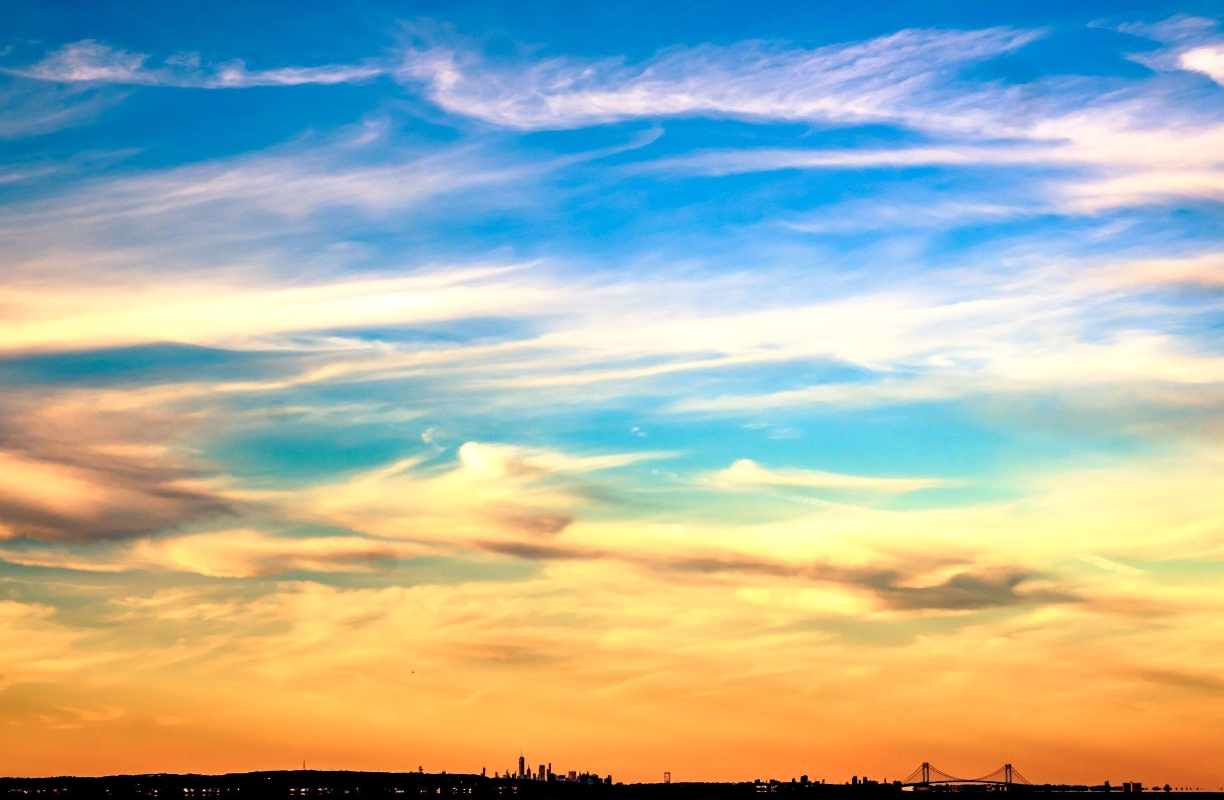 A sunset sky with clouds over a city skyline.