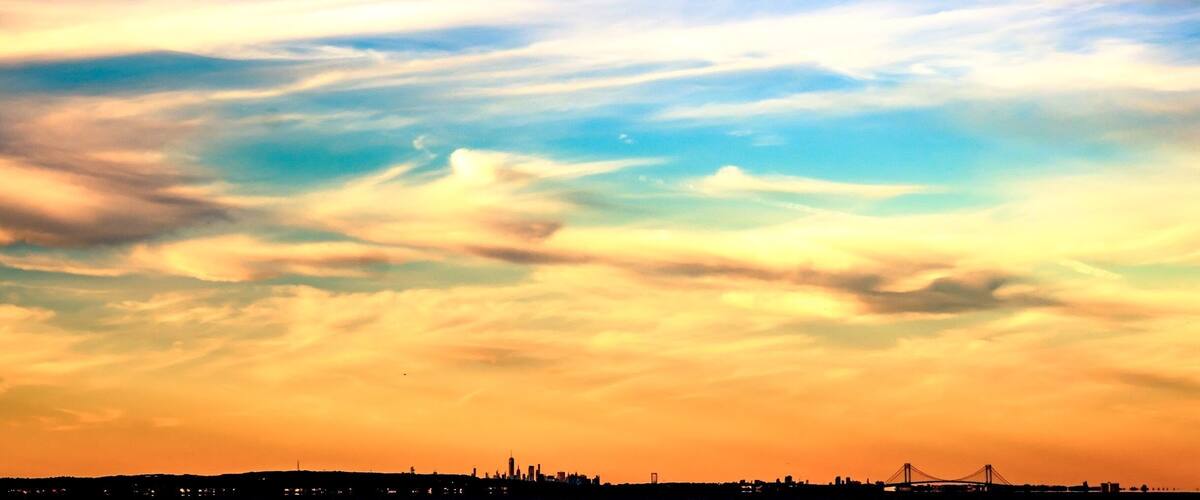 A sunset sky with clouds over a city skyline.