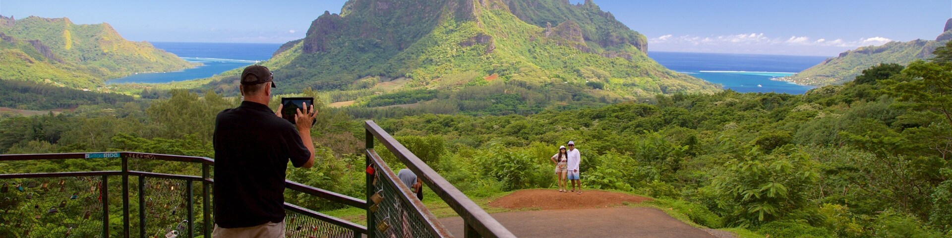 Un hombre fotografiando una vista de la montaña y el océano.