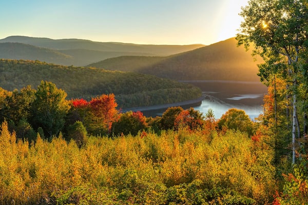 Eine Berglandschaft mit Herbstlaub und einem Fluss.