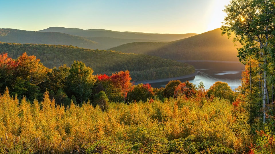 A mountainous landscape with autumn foliage and a river.