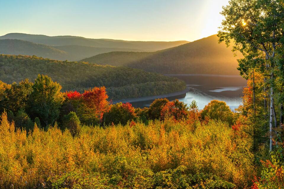 A mountainous landscape with autumn foliage and a river.