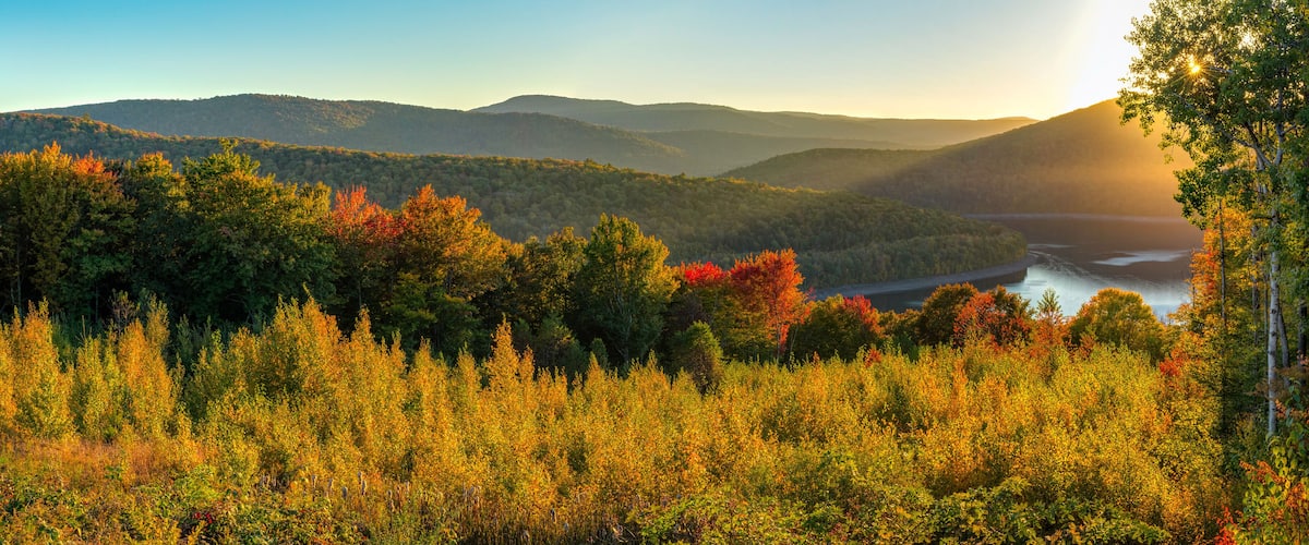 A mountainous landscape with autumn foliage and a river.