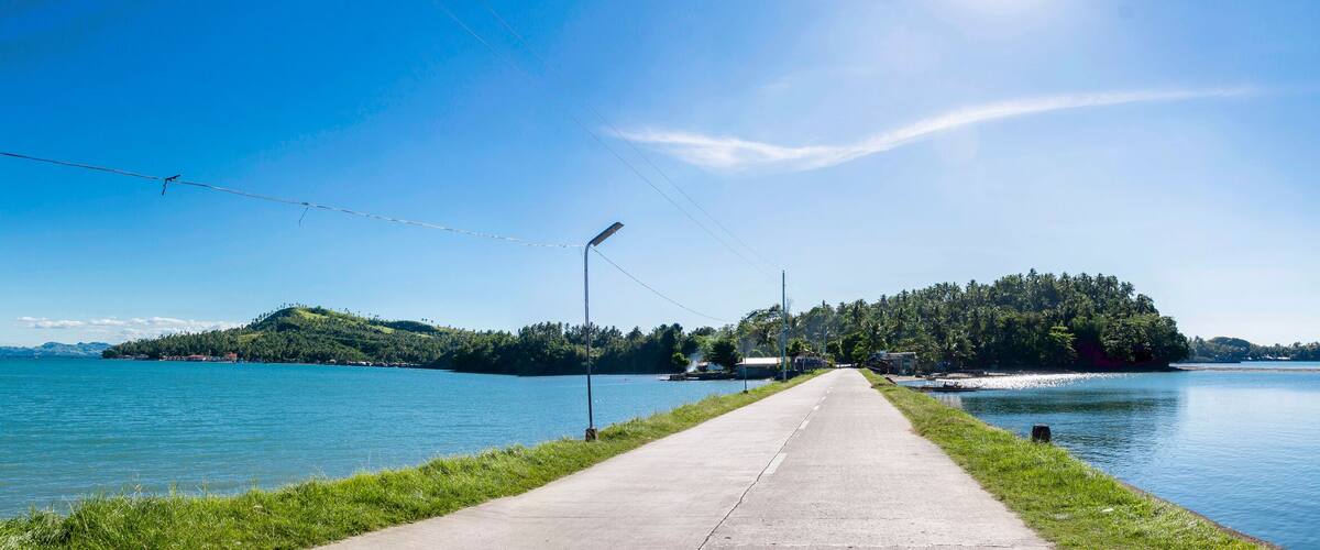 A clear road leading to a lake with a small island in the center.