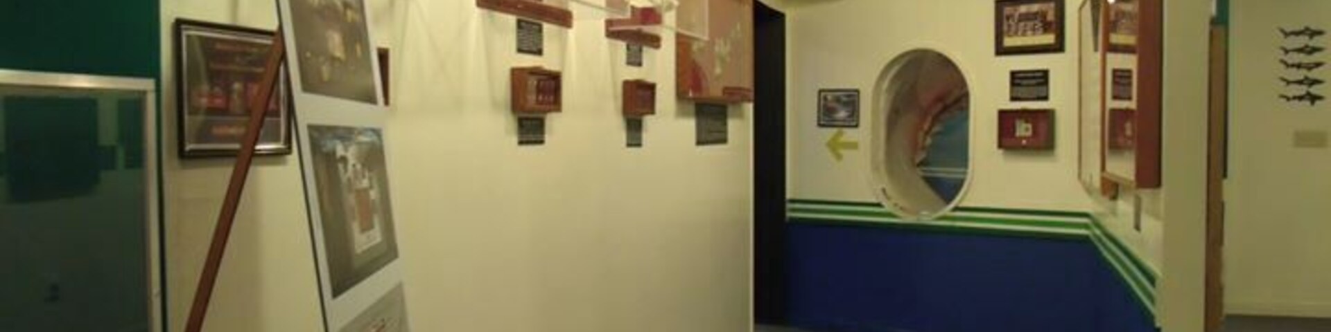 A hallway with framed exhibits and a blue stripe on the wall.