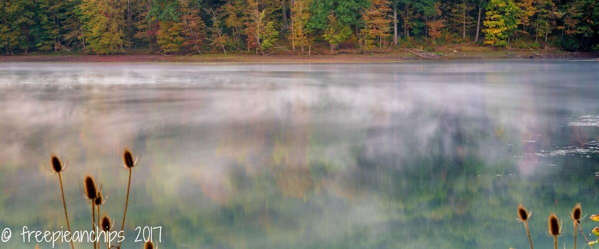 Mist swirls on water at first light stopped down for added affect as the first Autumn colours appear.