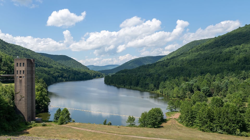A river winding through a forested valley with a concrete tower on the left.