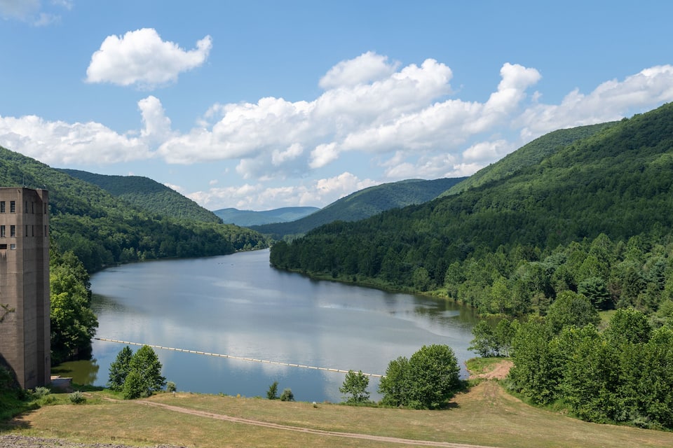 A river winding through a forested valley with a concrete tower on the left.