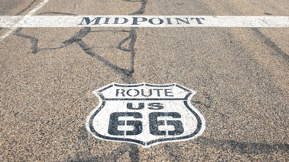 A road with a white line marking and a Route 66 sign.