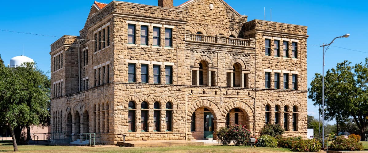 A large stone building with arched windows and a prominent chimney.